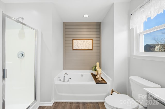 bathroom with shower with separate bathtub, hardwood / wood-style flooring, and toilet