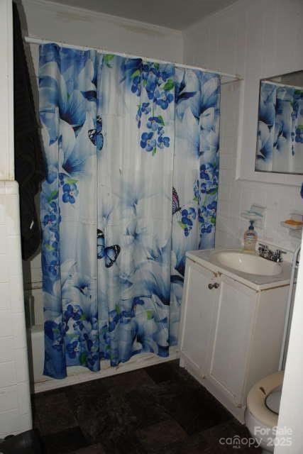 full bathroom with vanity, toilet, shower / bath combo with shower curtain, and tile walls