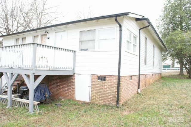 view of side of property featuring a wooden deck and a lawn