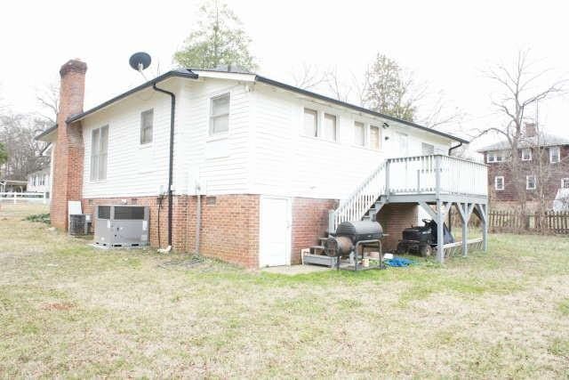 rear view of property featuring a yard, central air condition unit, and a deck