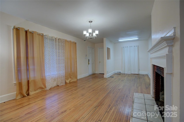 unfurnished living room with an inviting chandelier and light hardwood / wood-style flooring