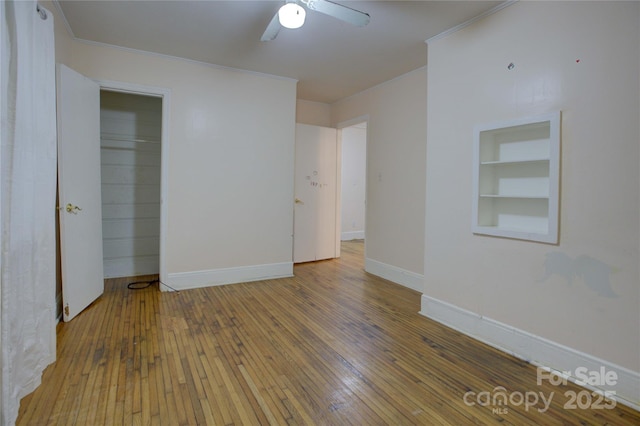 unfurnished room with hardwood / wood-style flooring, ornamental molding, and built in features