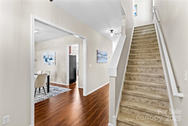 stairway with visible vents, baseboards, and wood finished floors