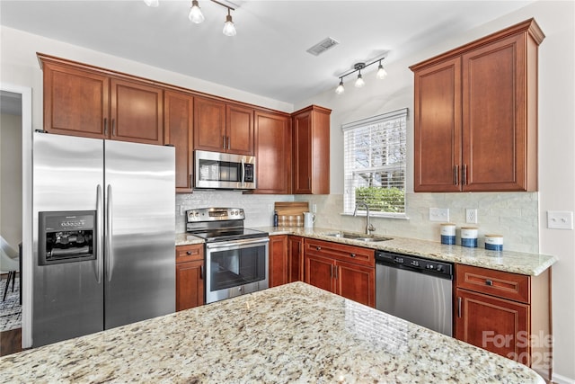 kitchen with stainless steel appliances, visible vents, decorative backsplash, a sink, and light stone countertops