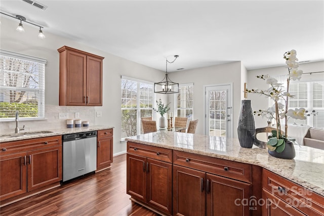 kitchen with dark wood-style flooring, a sink, stainless steel dishwasher, light stone countertops, and decorative light fixtures