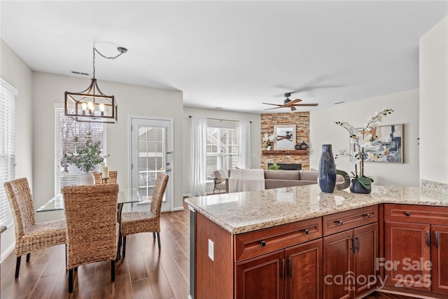 kitchen with light stone counters, a fireplace, wood finished floors, and pendant lighting