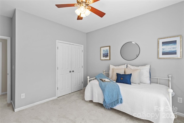 bedroom with light carpet, ceiling fan, a closet, and baseboards