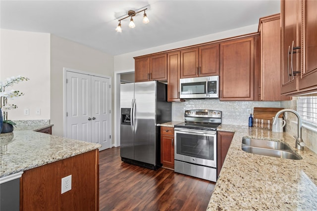 kitchen with dark wood-style flooring, decorative backsplash, appliances with stainless steel finishes, a sink, and light stone countertops