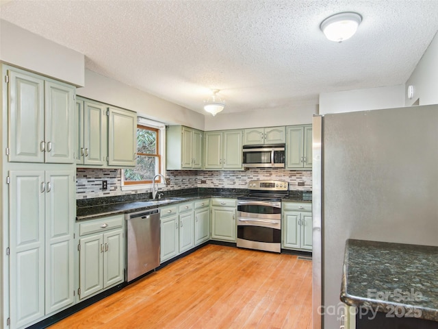 kitchen featuring tasteful backsplash, appliances with stainless steel finishes, green cabinets, and light wood-type flooring