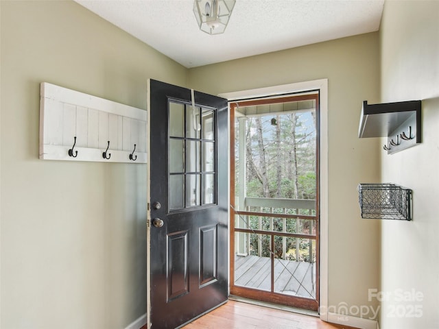 doorway to outside featuring light hardwood / wood-style flooring and a textured ceiling