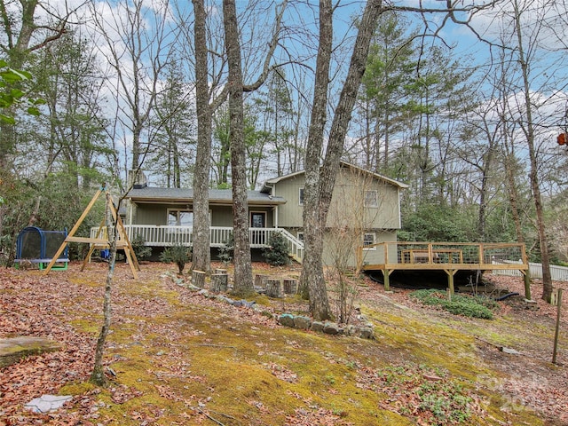 rear view of property featuring a deck and a trampoline