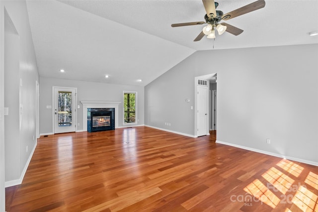 unfurnished living room with a ceiling fan, wood finished floors, a high end fireplace, baseboards, and vaulted ceiling