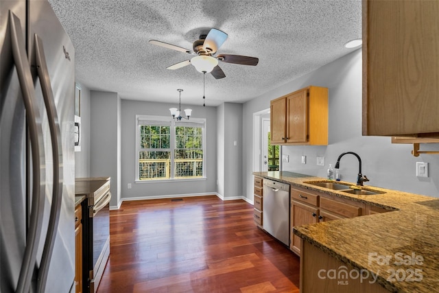 kitchen featuring a sink, baseboards, ceiling fan with notable chandelier, stainless steel appliances, and dark wood-style flooring