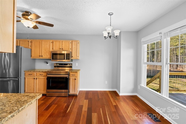 kitchen featuring ceiling fan with notable chandelier, a textured ceiling, appliances with stainless steel finishes, baseboards, and dark wood-style flooring