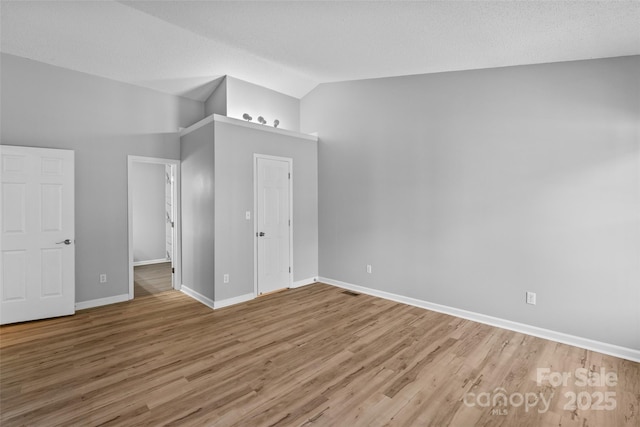 unfurnished bedroom featuring vaulted ceiling, wood finished floors, and baseboards