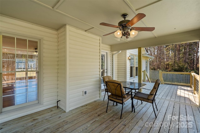 wooden terrace with outdoor dining area and a ceiling fan