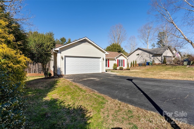 ranch-style home with driveway, an attached garage, and a front yard