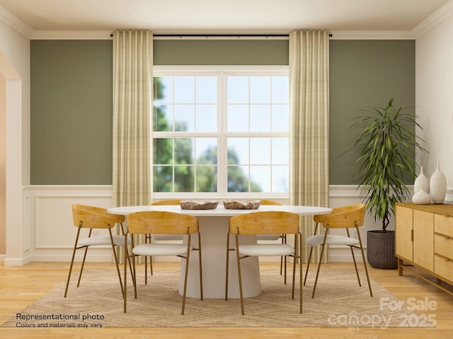 dining area with a wainscoted wall, wood finished floors, and ornamental molding