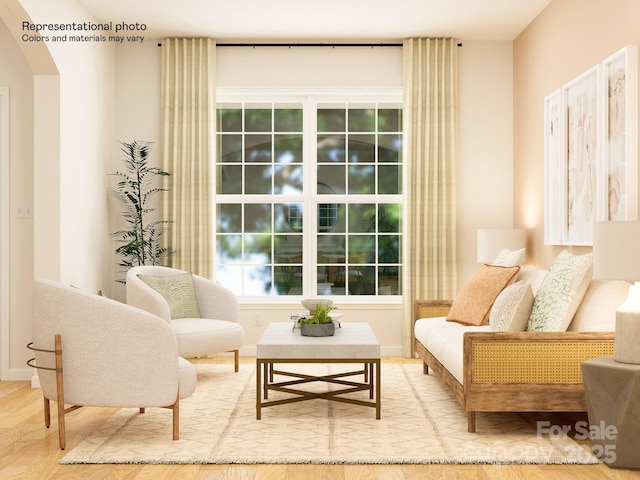 sitting room featuring baseboards, arched walkways, and wood finished floors