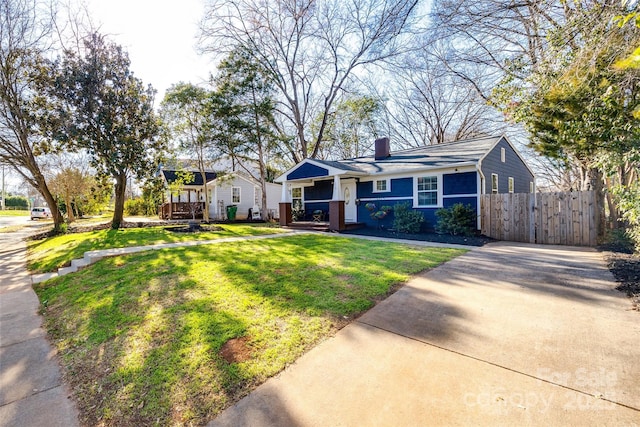 bungalow with driveway, fence, a chimney, and a front lawn