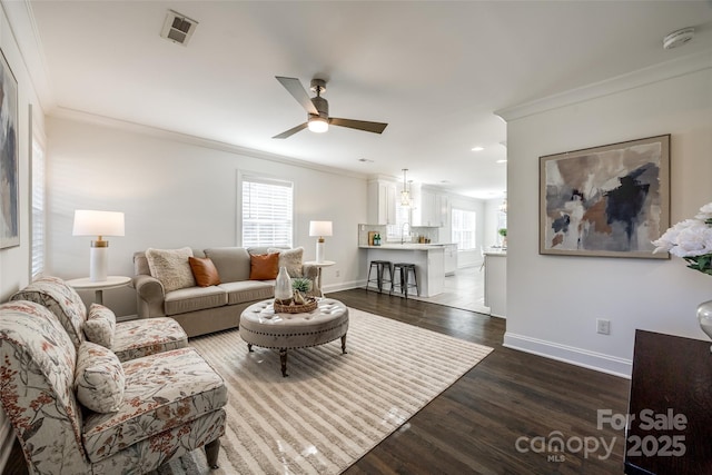 living area with a wealth of natural light, visible vents, and crown molding