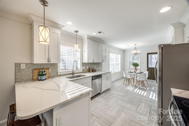 kitchen featuring stainless steel appliances, crown molding, a sink, and backsplash