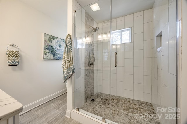 full bathroom with a stall shower, baseboards, and wood finished floors