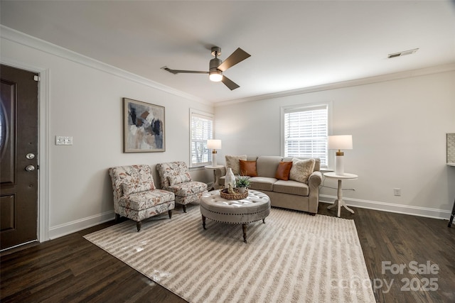 living area featuring ceiling fan, dark wood-style flooring, visible vents, baseboards, and ornamental molding