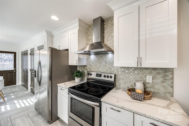 kitchen featuring appliances with stainless steel finishes, ornamental molding, light stone countertops, wall chimney range hood, and white cabinetry