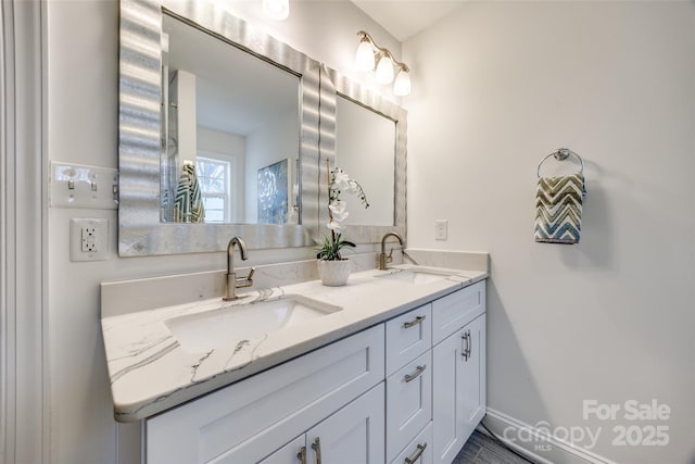 full bath with a sink, baseboards, and double vanity