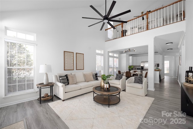 living room featuring a towering ceiling, hardwood / wood-style floors, and ceiling fan