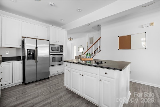 kitchen with stainless steel appliances, dark hardwood / wood-style floors, a kitchen island, and white cabinets