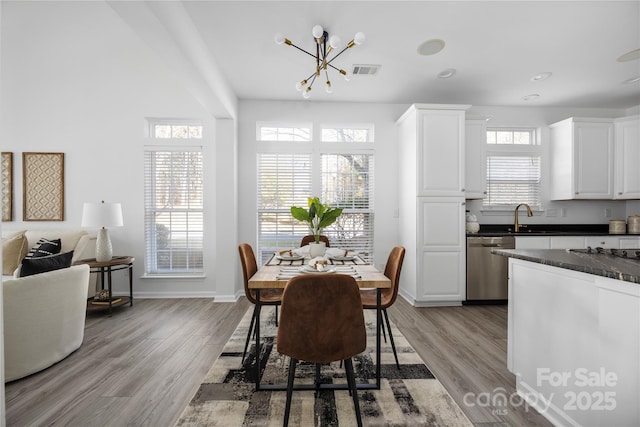 dining area with an inviting chandelier, sink, and light hardwood / wood-style floors