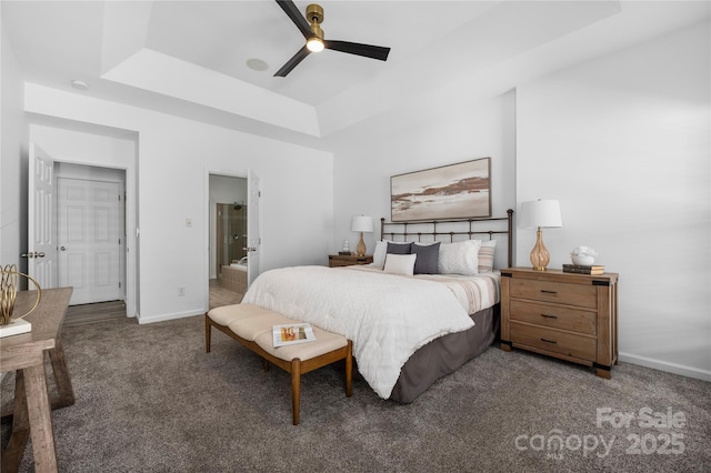 bedroom with ceiling fan, a tray ceiling, and dark carpet