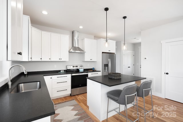 kitchen featuring a center island, white cabinetry, stainless steel appliances, wall chimney exhaust hood, and sink