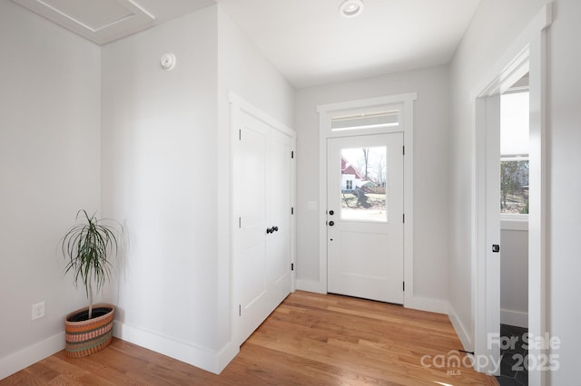 foyer entrance featuring a healthy amount of sunlight, baseboards, and light wood-style floors