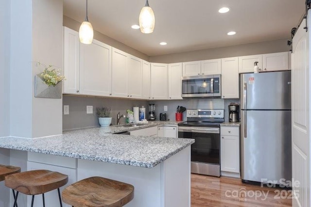 kitchen with appliances with stainless steel finishes, white cabinets, a kitchen breakfast bar, and kitchen peninsula