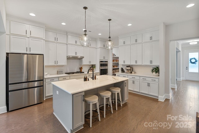 kitchen with white cabinetry, stainless steel appliances, and a center island with sink