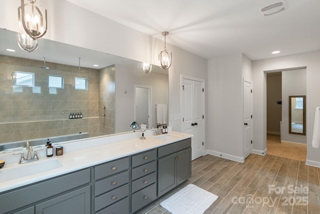 bathroom featuring tiled shower, vanity, hardwood / wood-style floors, and a notable chandelier