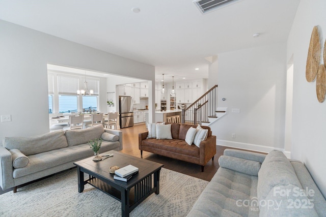 4159 Millstream Rd, Denver, NC 28037 - living room with visible vents, baseboards, a chandelier, stairway, and light wood-style flooring