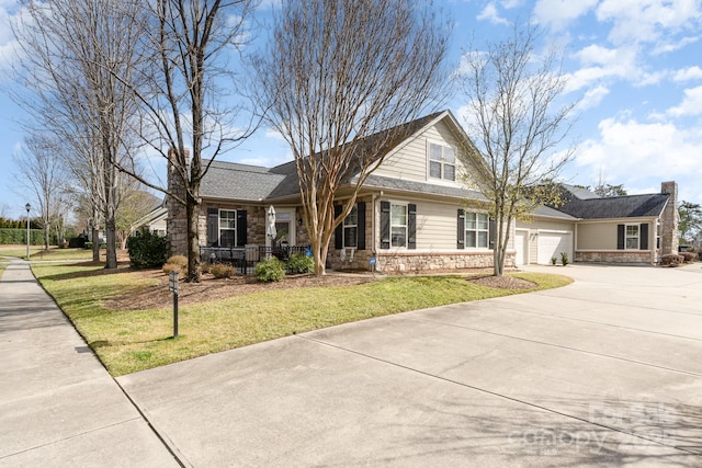 view of front of home featuring covered porch, concrete driveway, a front yard, a garage, and stone siding