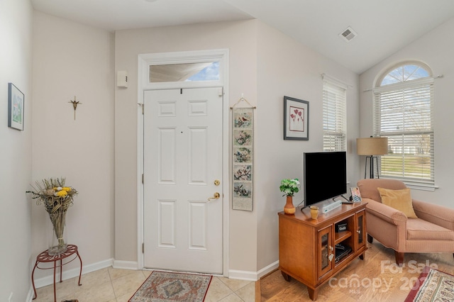 entrance foyer with lofted ceiling, light tile patterned floors, baseboards, and visible vents