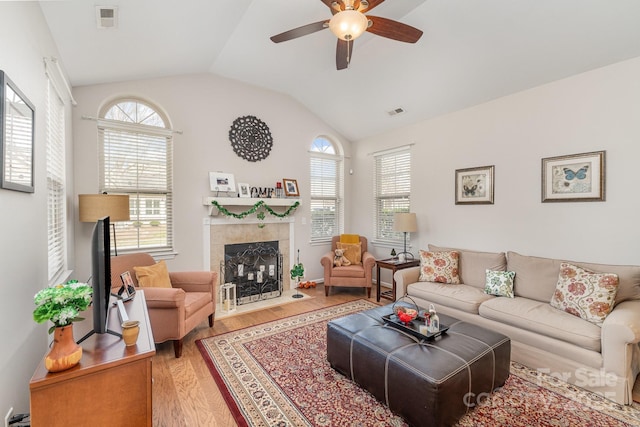 living area with plenty of natural light, visible vents, vaulted ceiling, and wood finished floors