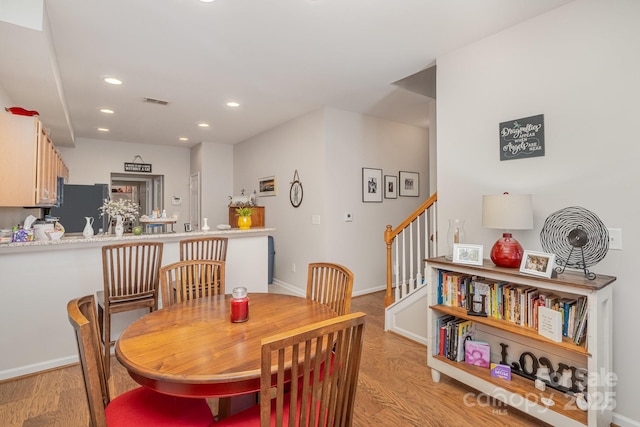 dining room with baseboards, visible vents, light wood-style flooring, stairs, and recessed lighting