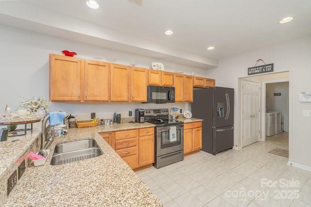 kitchen with recessed lighting, washer / clothes dryer, a sink, light stone countertops, and black appliances