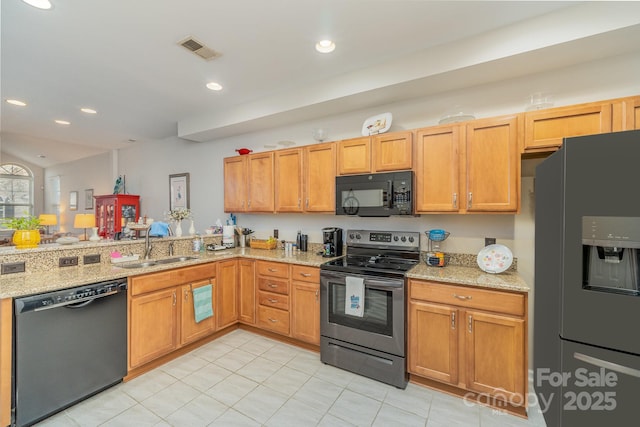 kitchen with black appliances, light stone counters, a sink, and visible vents