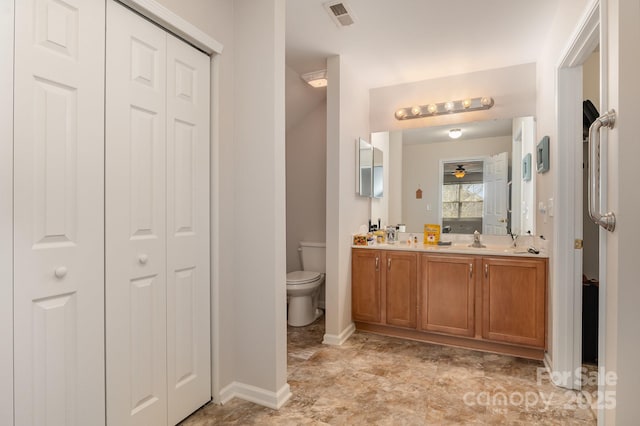 bathroom with double vanity, a closet, visible vents, toilet, and a sink