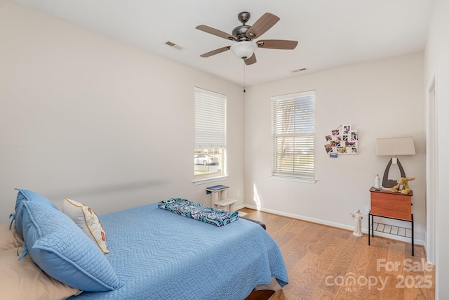 bedroom with light wood-style flooring, visible vents, ceiling fan, and baseboards