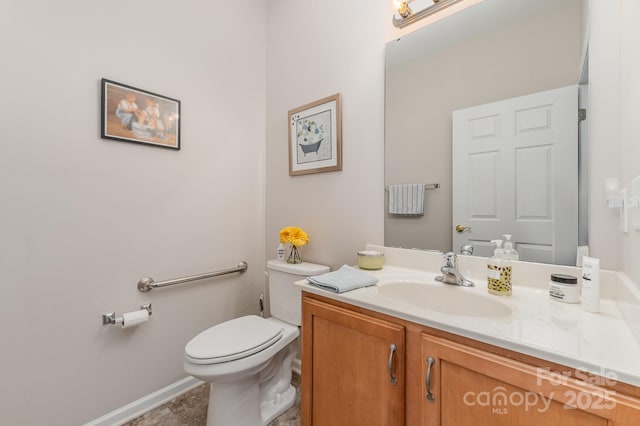 half bathroom featuring toilet, baseboards, and vanity