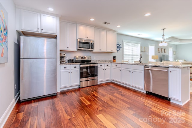 kitchen featuring white cabinetry, hanging light fixtures, dark hardwood / wood-style floors, kitchen peninsula, and stainless steel appliances